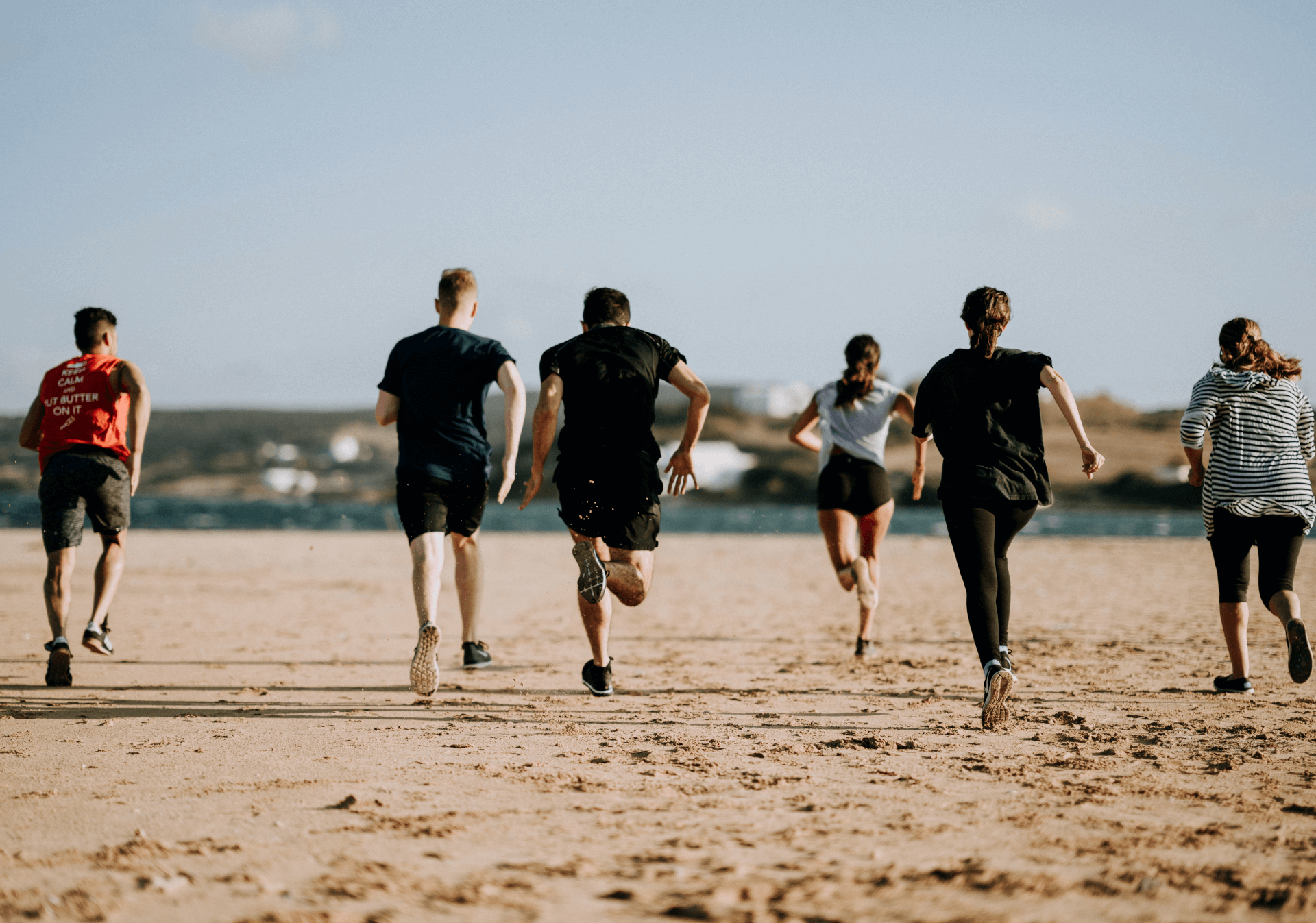a group of people running on a beach